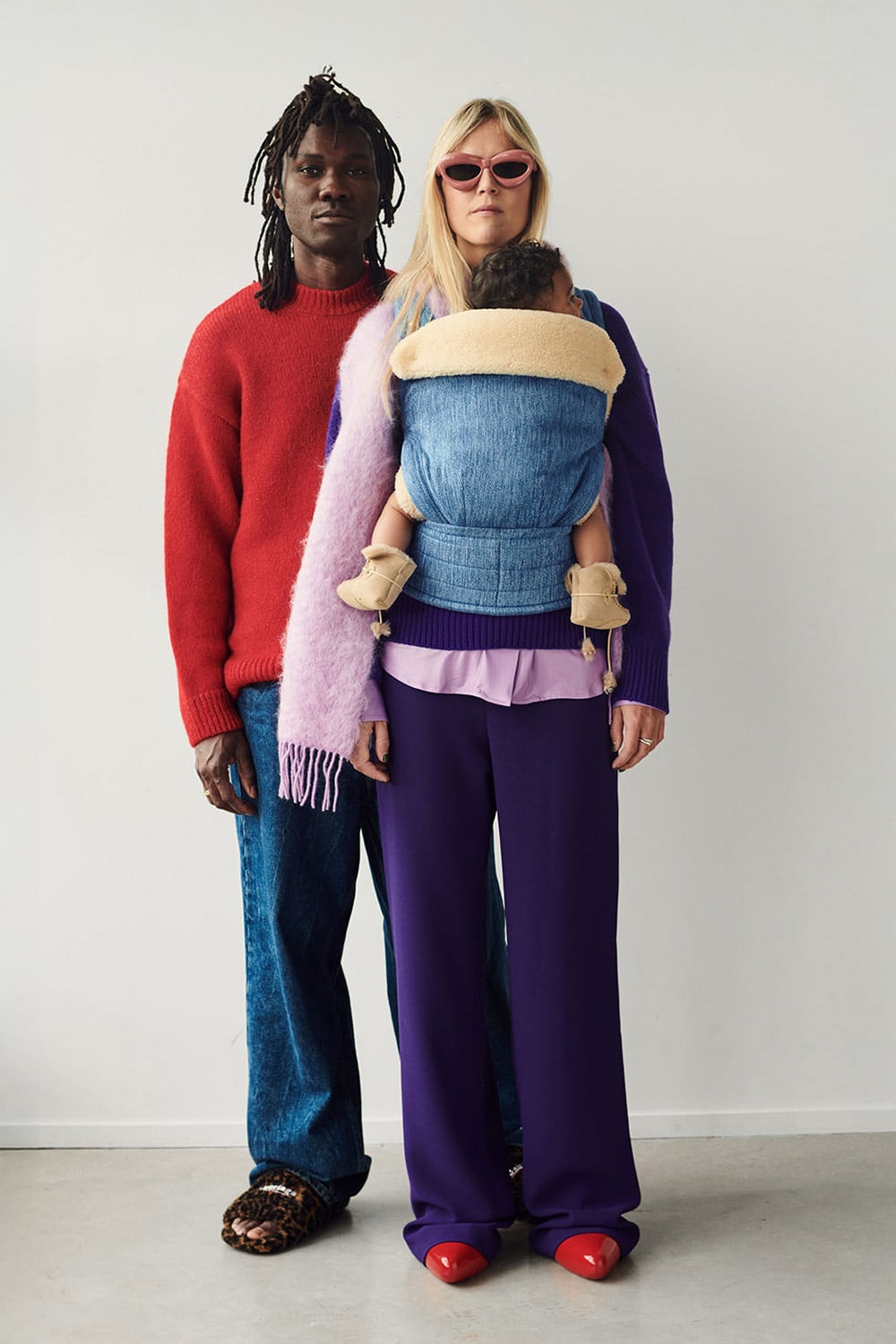 A female model wearing a denim baby carrier with a light beige attachable insert in 100% lambskin