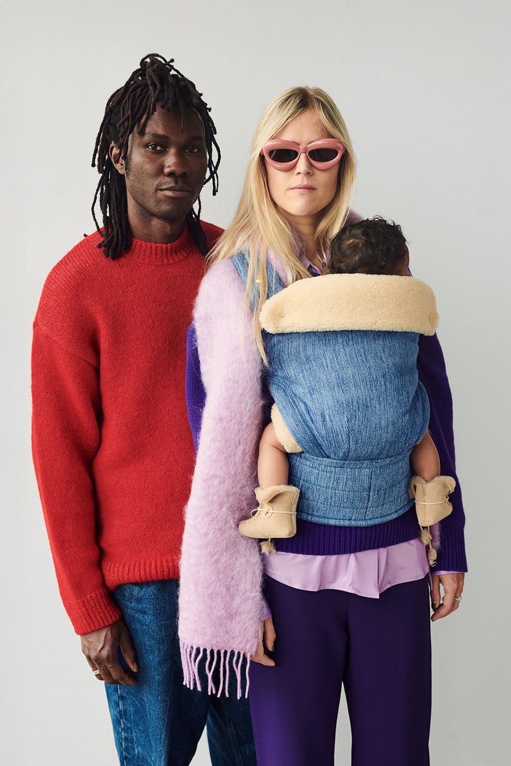 A female model wearing a denim baby carrier with a light beige attachable insert in 100% lambskin